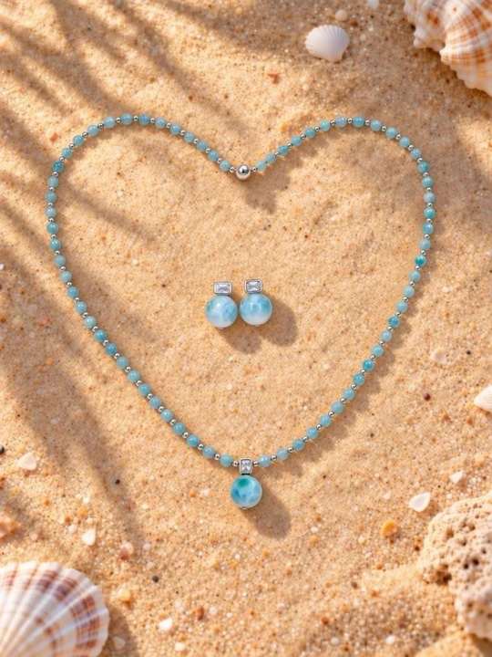 Larimar necklace and earrings arranged in a heart on the beach