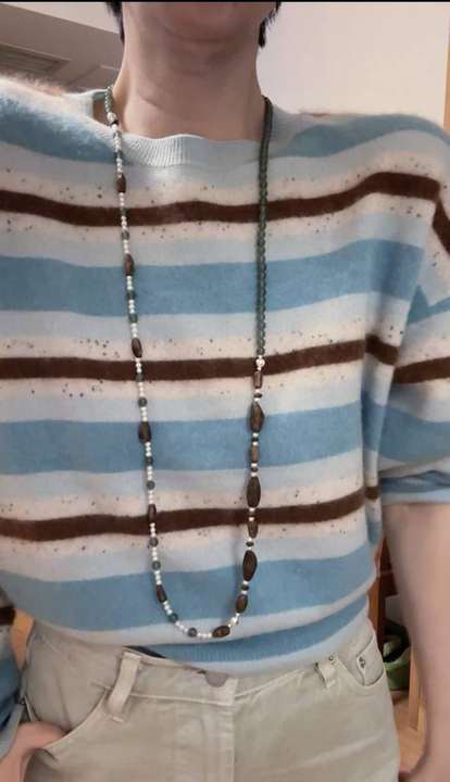 Sweater necklace worn long over a striped knit